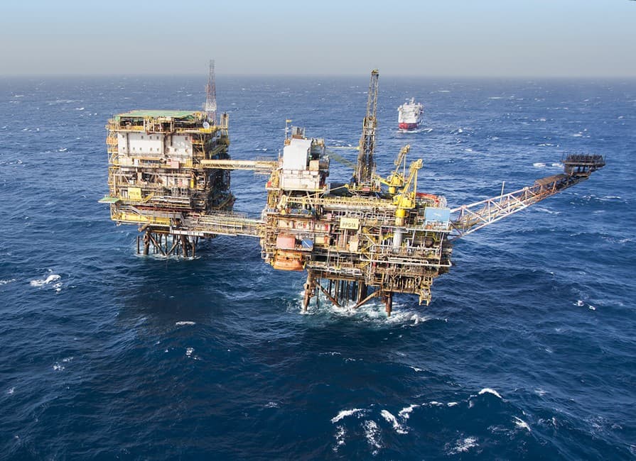 Plataforma de extração de petróleo operando em alto mar sob céu claro.