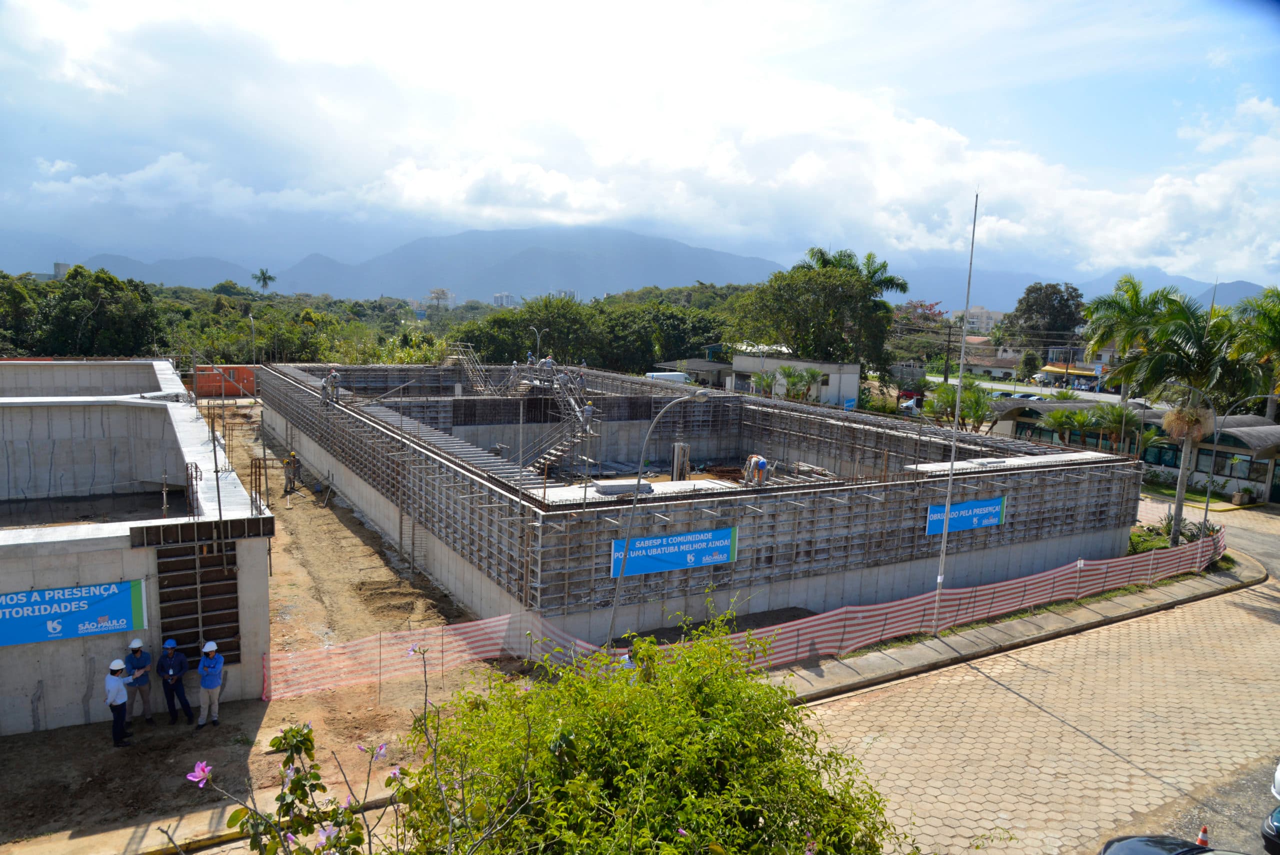Canteiro de obras de infraestrutura de saneamento da Sabesp com estruturas de concreto e trabalhadores.
