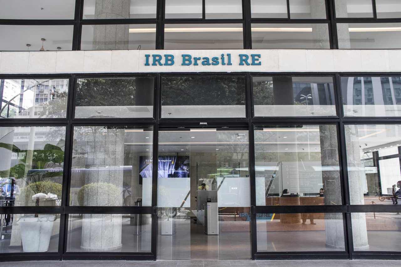 Fachada do edifício do IRB Brasil RE com portas de vidro e letreiro da empresa.