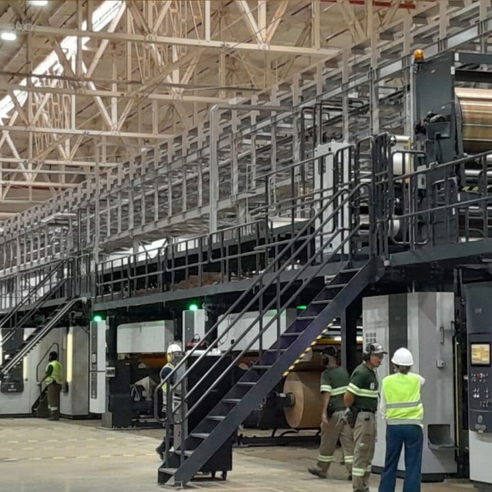 Moderna máquina de papel em galpão industrial com logotipos da Klabin