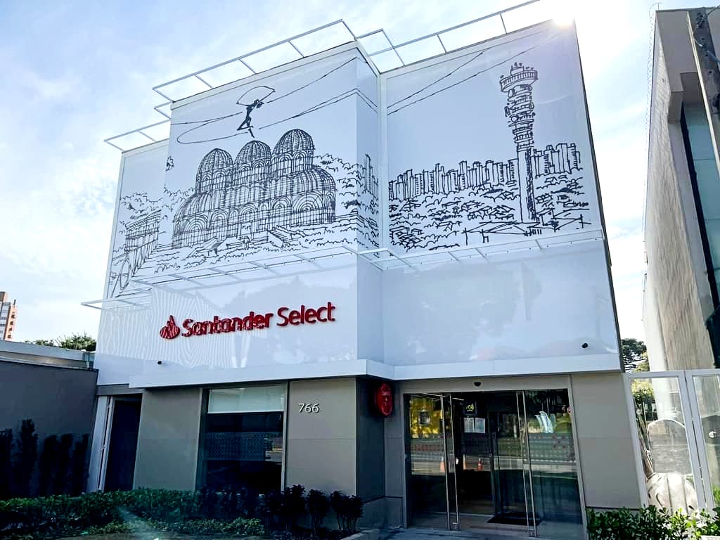 Fachada de agência do banco Santander Select com logotipo vermelho em destaque e painel artístico